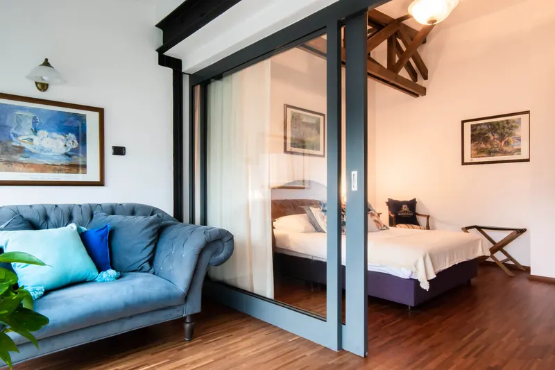 Sofa beside a glazed partition with the bedroom behind — Deluxe Apartment, Hornigold
