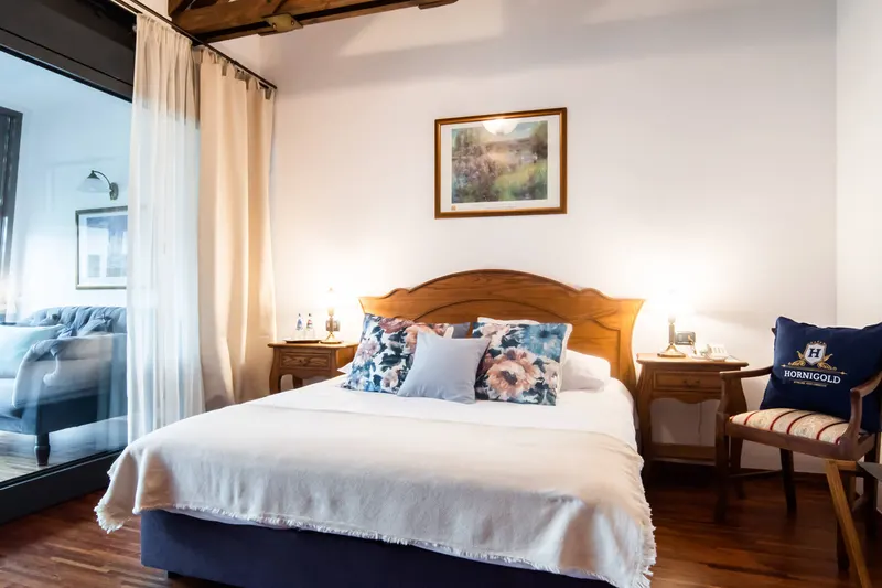 Bed with a wooden headboard and bedside lamps — Deluxe Apartment, Hornigold