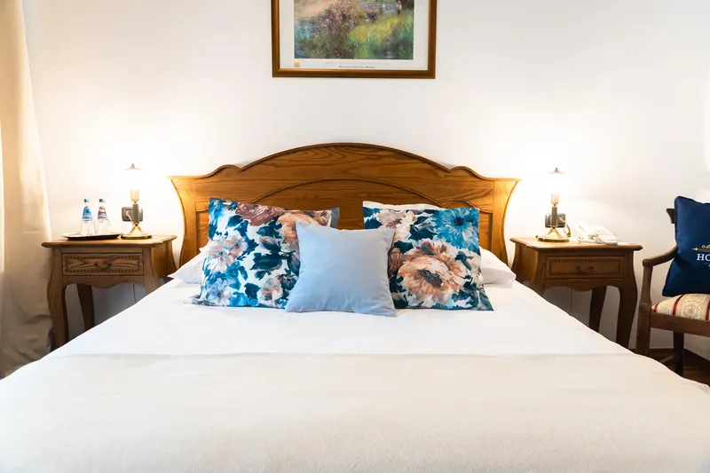 Front view of the bed with pictures above the headboard — Deluxe Apartment, Hornigold