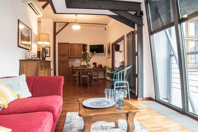 Living room with a red sofa, glazing and a table at the far end — Deluxe Apartment, Hornigold