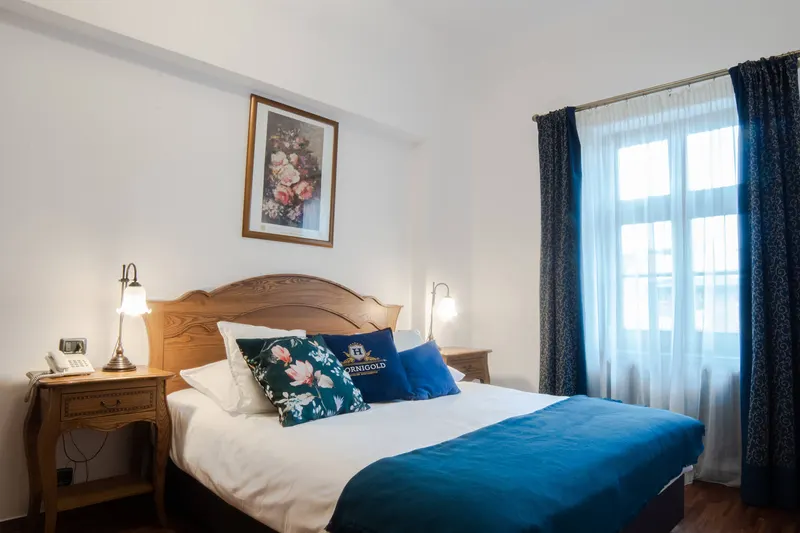 Bed beside a curtained window — Prestige Deluxe Apartment, Hornigold