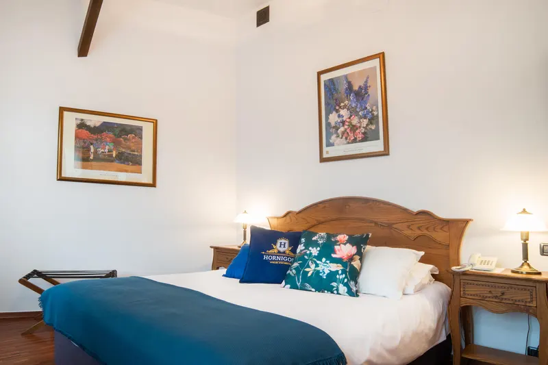Front view of the bed with pictures above the headboard — Prestige Deluxe Apartment, Hornigold