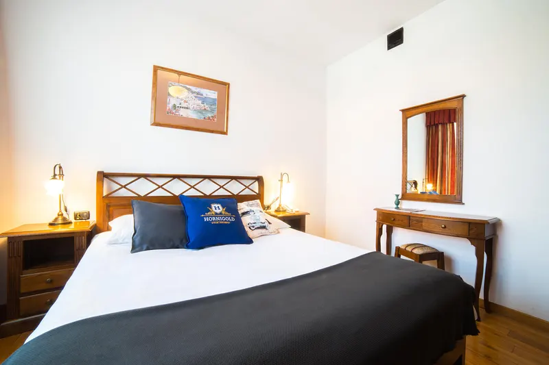 Bett mit Holzkopfteil und Nachttischlampen — Suite, Hornigold